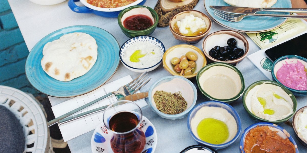 A Turkish meze spread on a table with tea, olives, hummus and flatbread