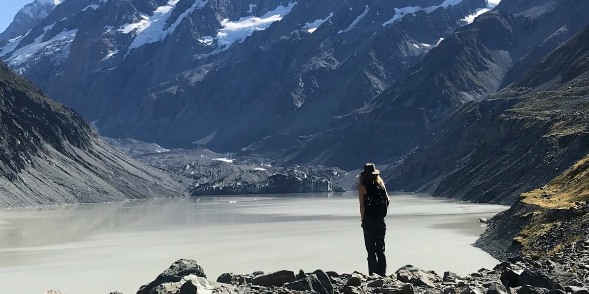 A solo hiker looking out over a glacier lake in New Zealand
